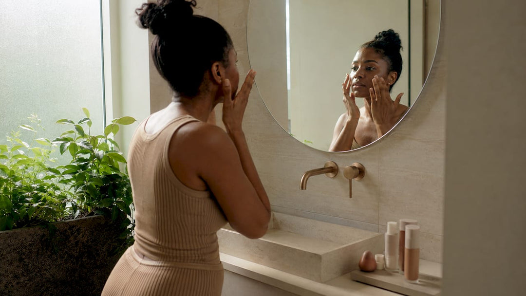 Woman applying makeup primer at vanity