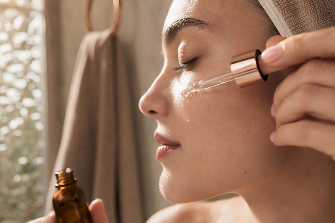 Hands applying niacinamide serum on cheek