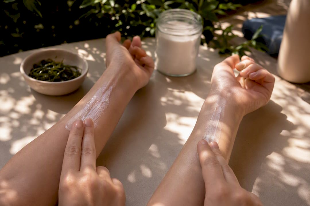 Hands applying mineral and chemical sunscreen on arms