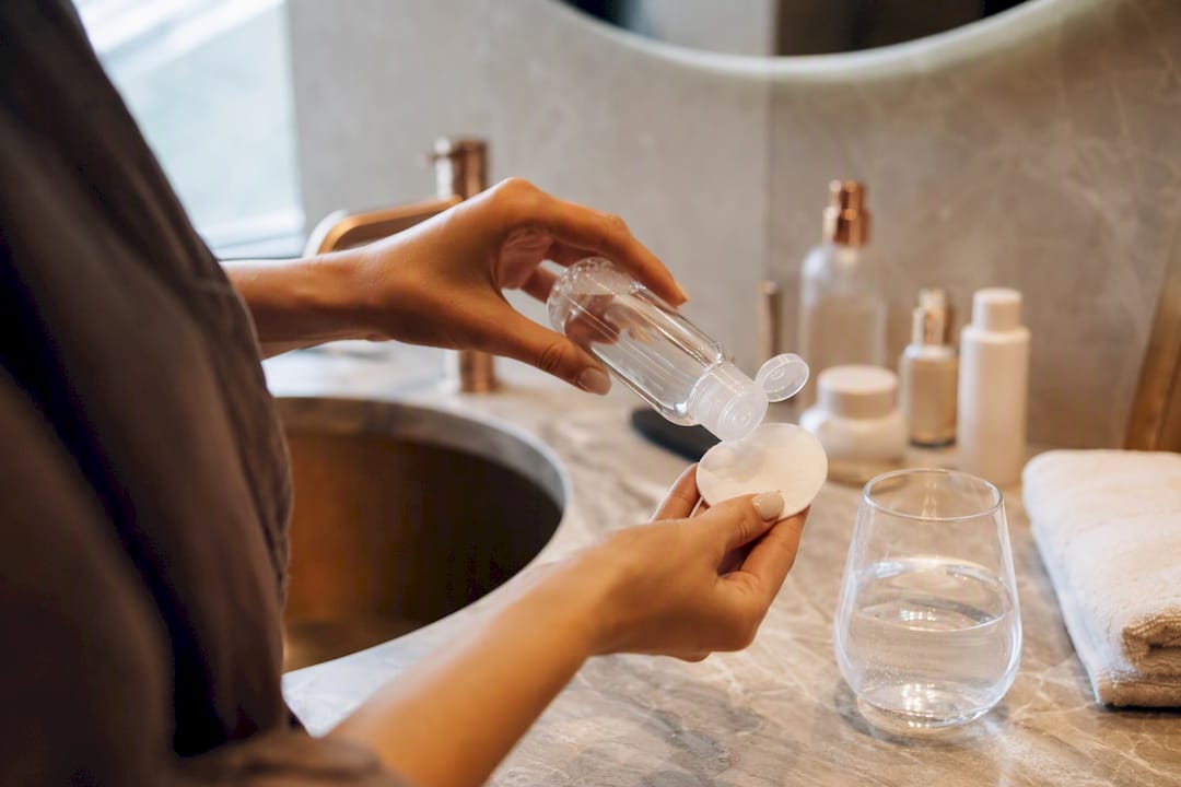 Hand wiping face with micellar water cotton pad