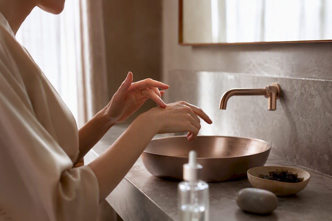 Hands applying hyaluronic acid serum to skin