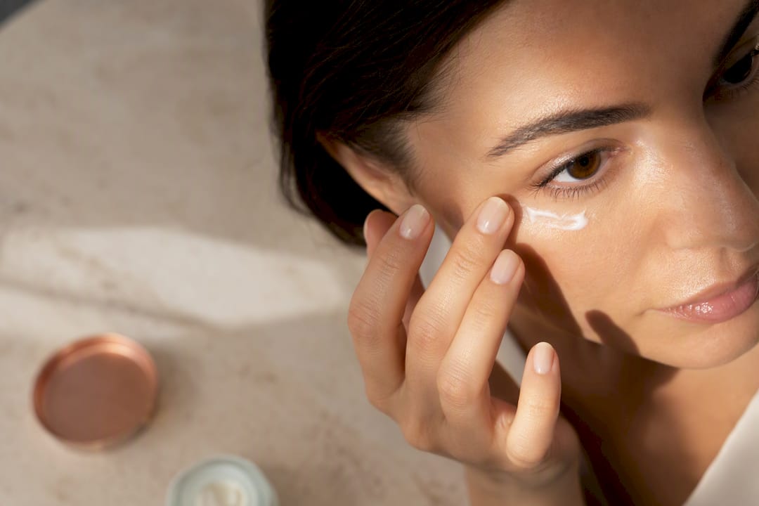 Woman applying eye cream beneath eye