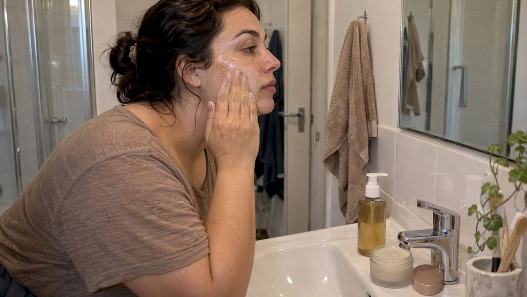 Woman cleansing makeup beside oil and balm