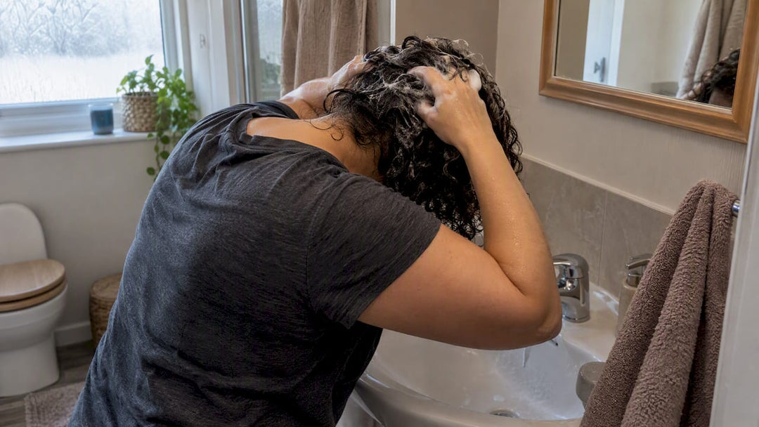 Woman washing her curly hair at a basin