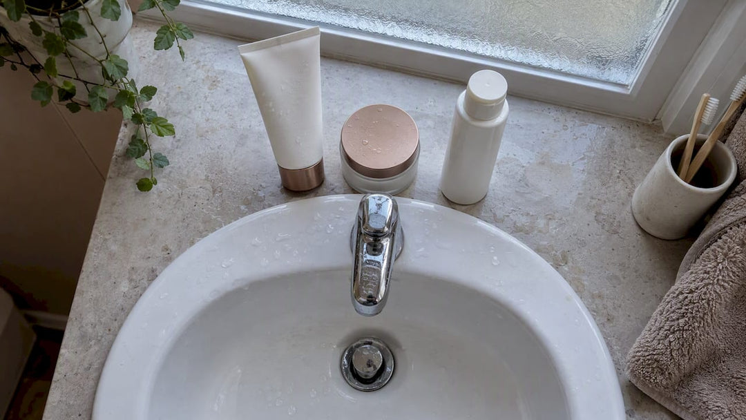 Three skincare essentials beside a bathroom basin
